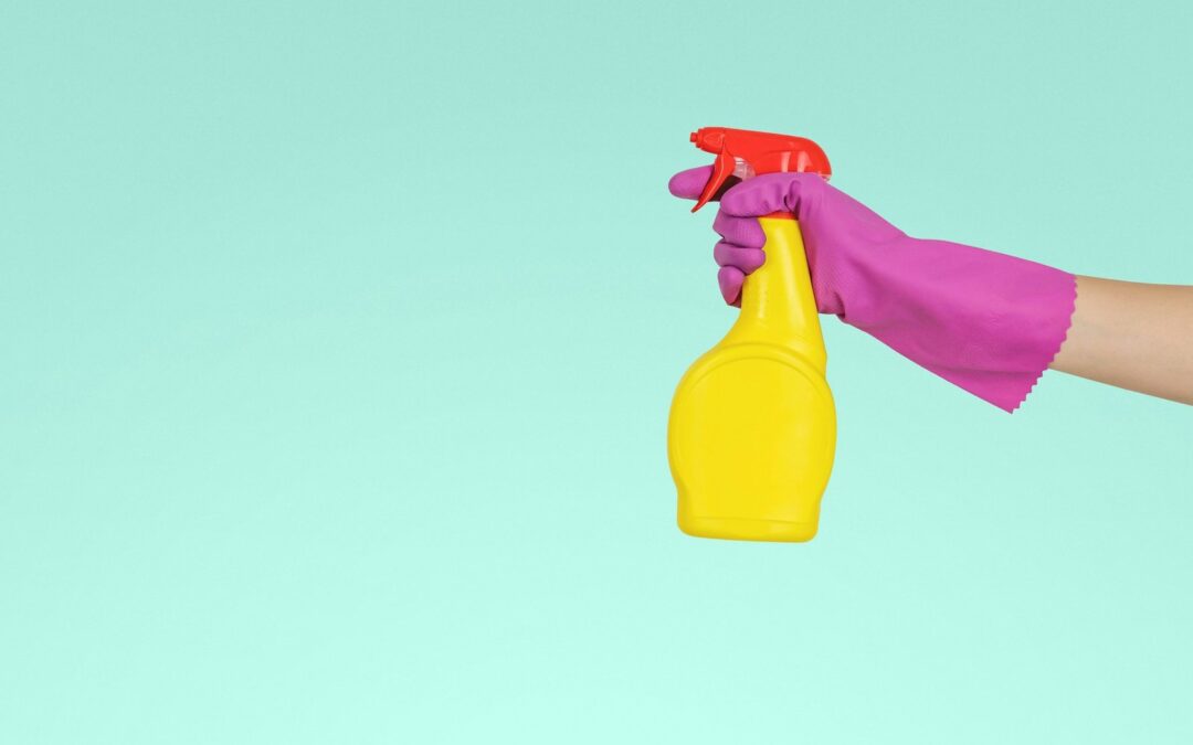Spruzzino con detergente impugnato con un guanto per le pulizie professionali
