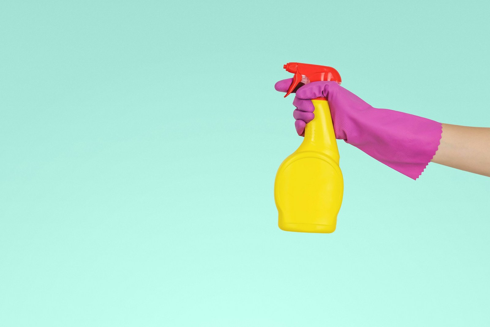 Spruzzino con detergente impugnato con un guanto per le pulizie professionali